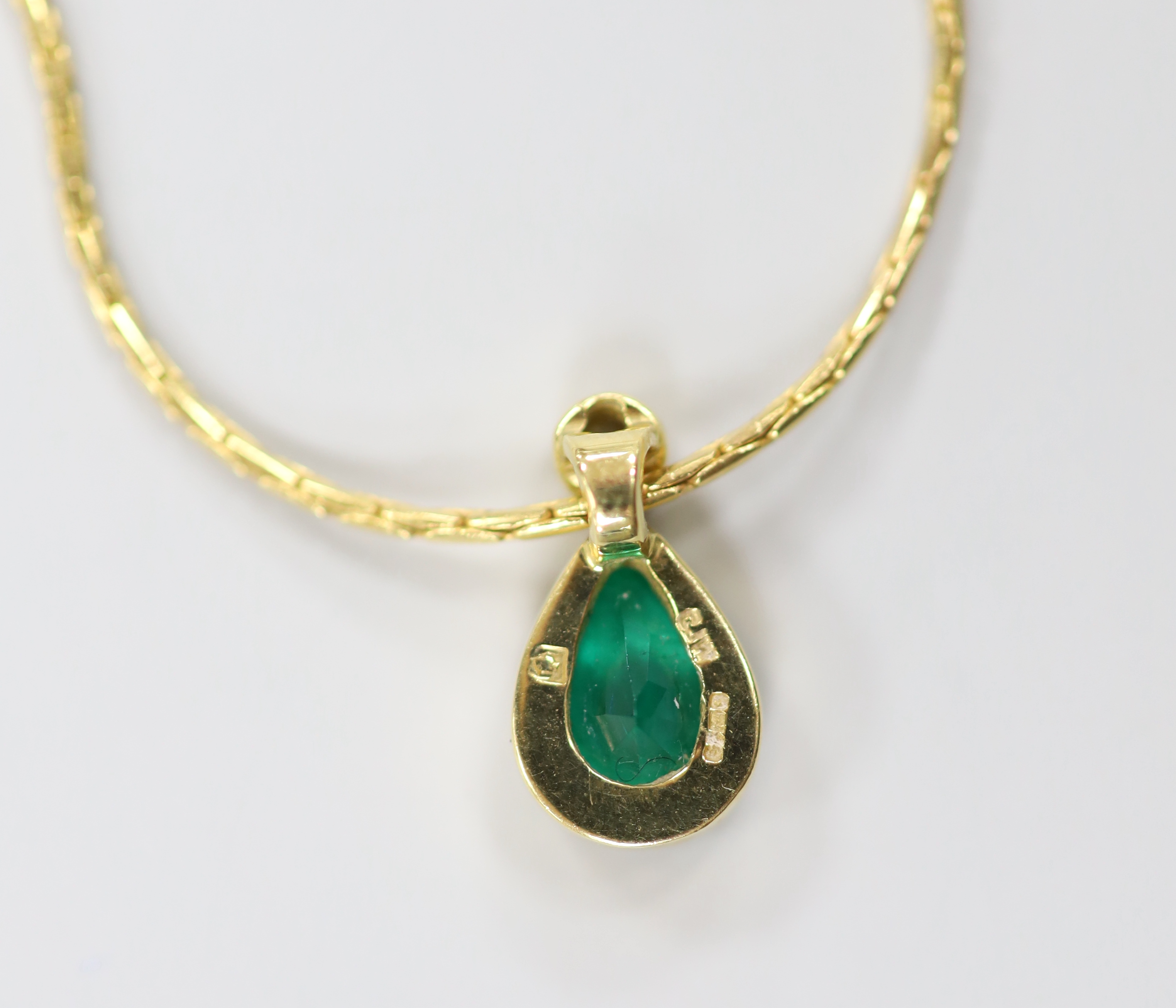 A modern 18ct gold, pear cut emerald and round cut diamond set pendant, 14mm, on an 18ct gold chain, 38cm, gross weight 6.3 grams.